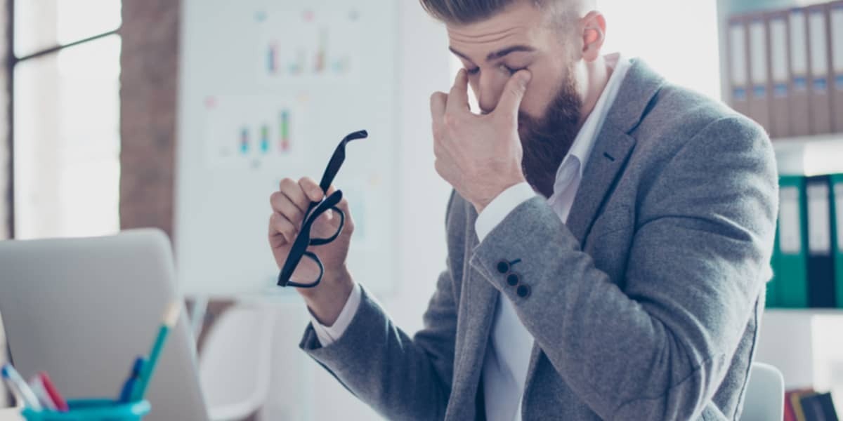 Man die voor laptop zit, wrijft in zijn ogen