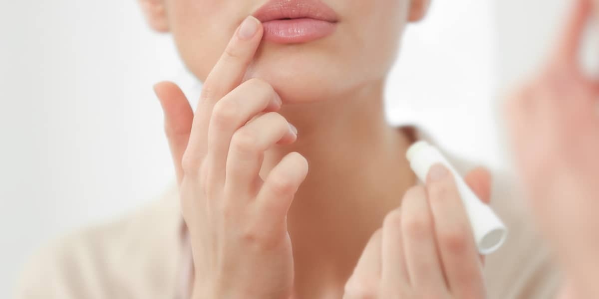 Femme frotte les lèvres avec du rouge à lèvres