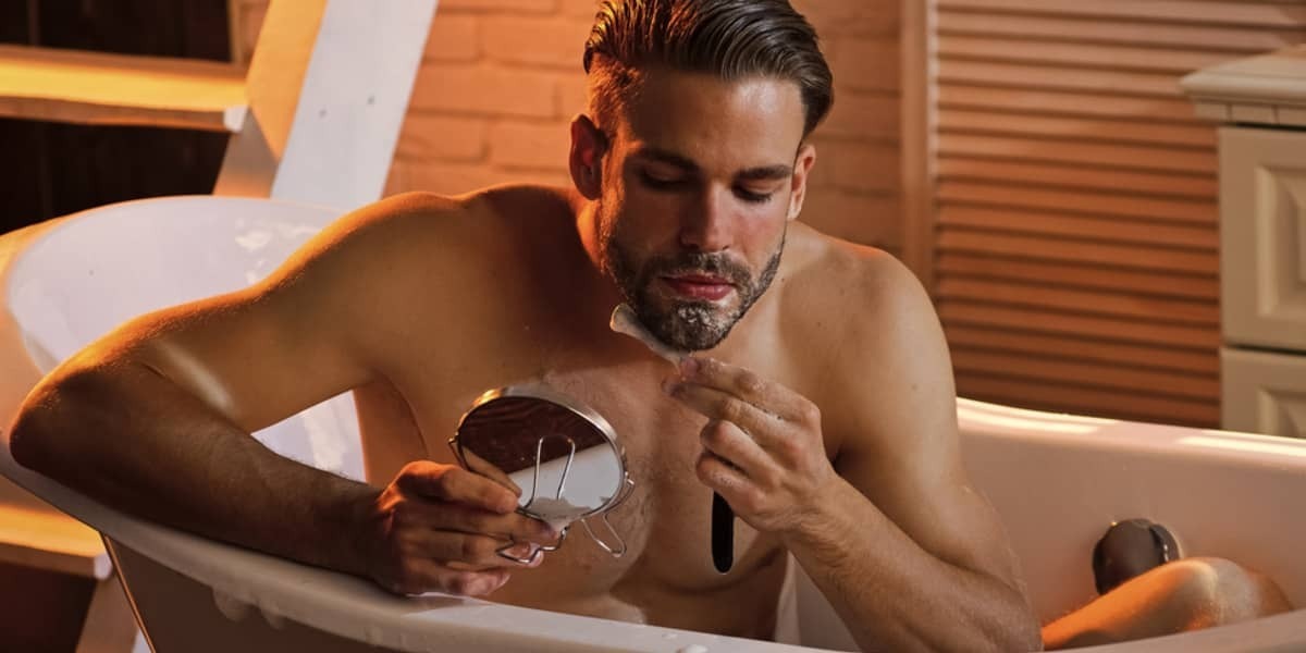 Man scheert zijn baard in het bad