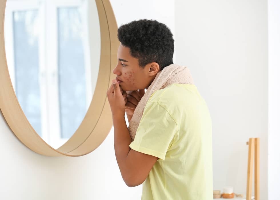 Adolescent duwt puist uit voor spiegel