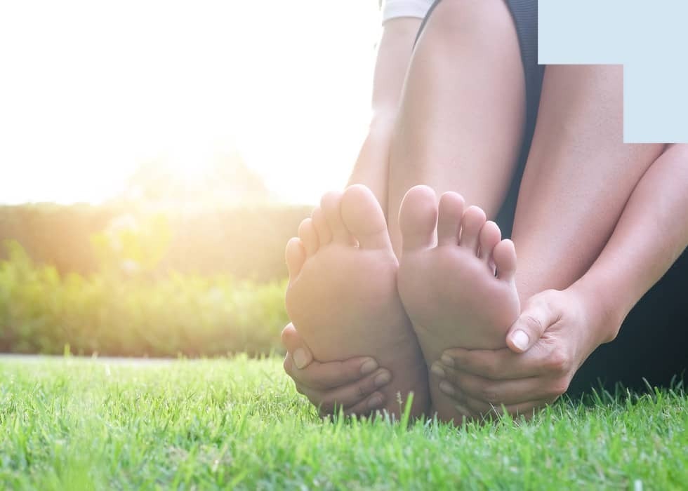 Les pieds bien entretenus sont tenus dans l'herbe avec les mains